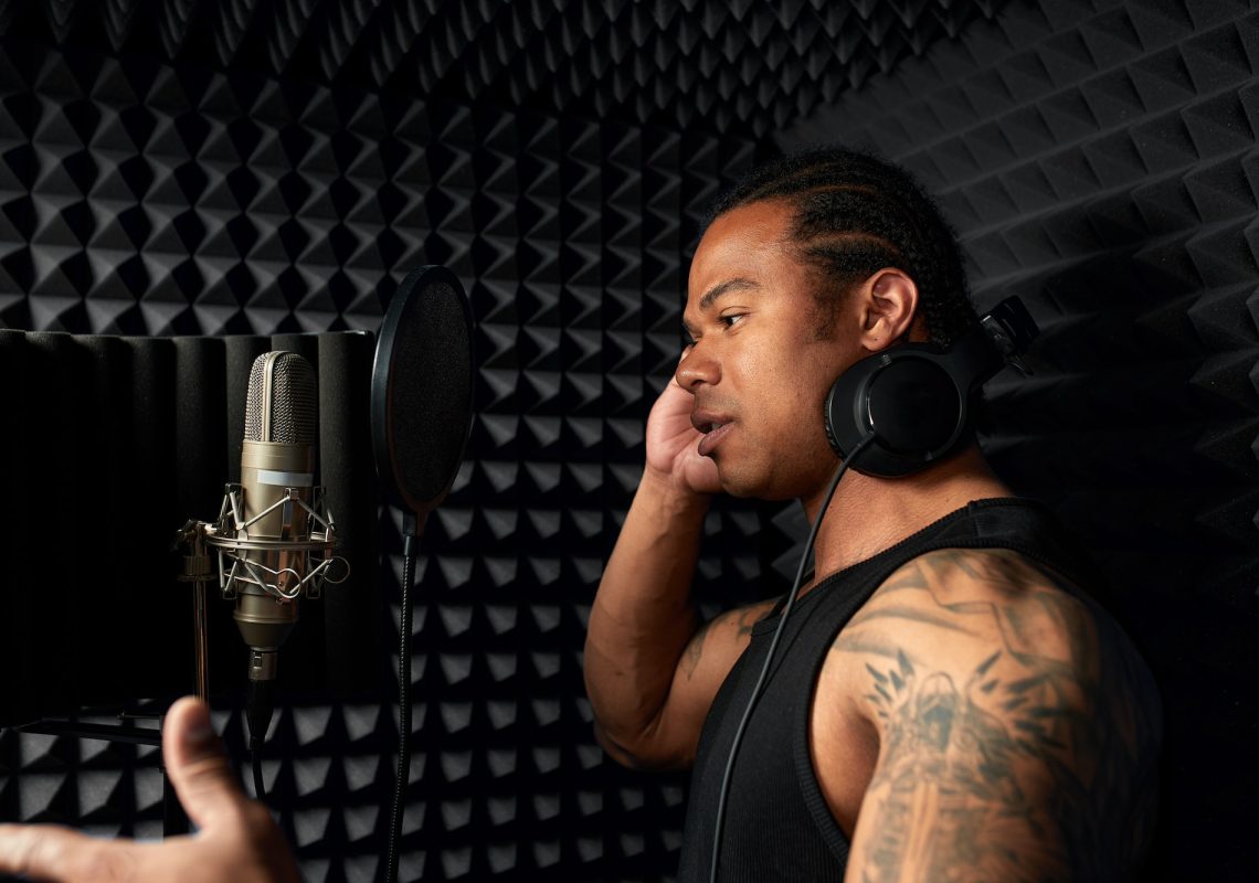 Young African American singer in a recording studio, recording a podcast, recording a song, young